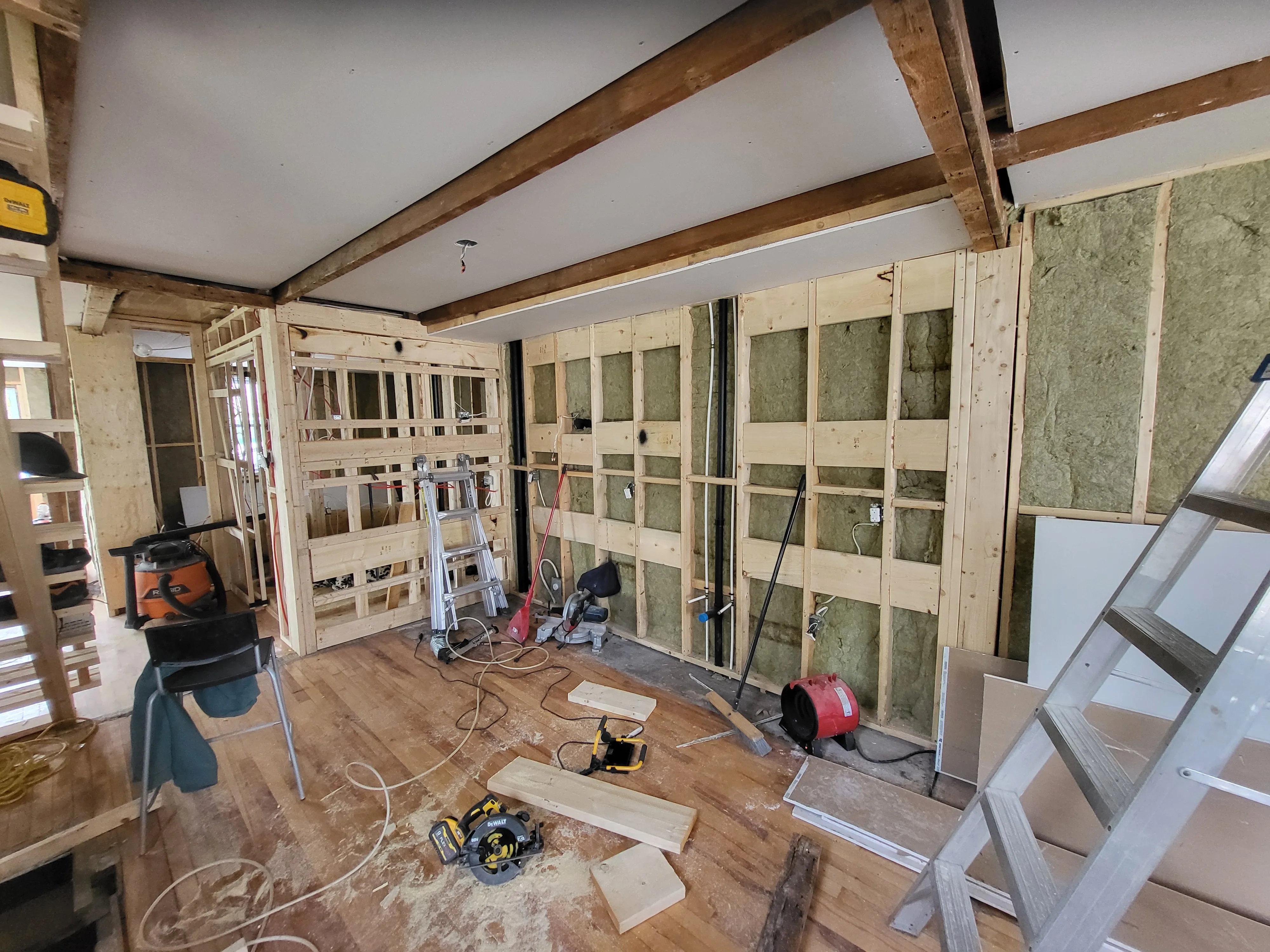 Rénovation intérieure en cours avec plafond cathédrale à poutres de bois apparentes