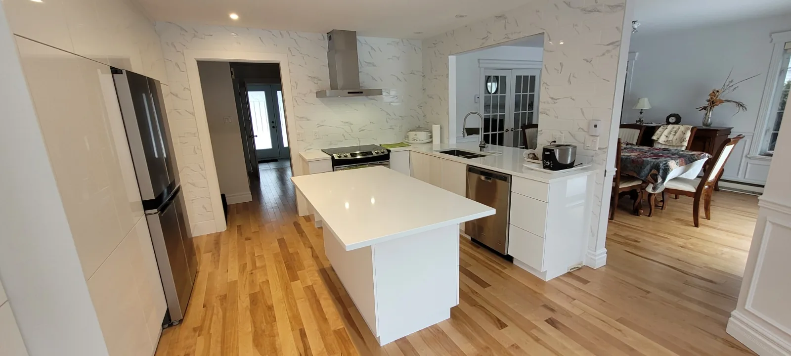 Cuisine terminée avec îlot de quartz, plancher de bois franc et coin repas